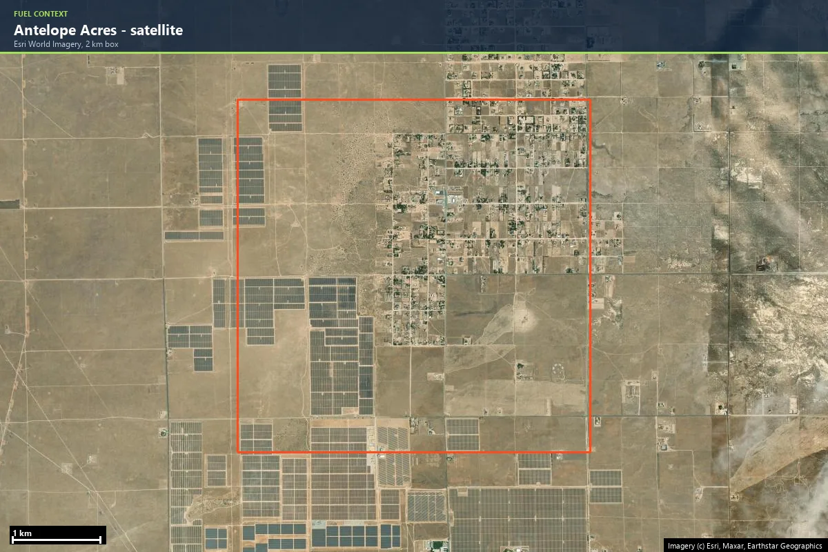 Satellite view of Antelope Acres, California: scattered rural homes on large lots surrounded by open cured grassland, with solar farms to the south and west, 2 km box outlined in orange